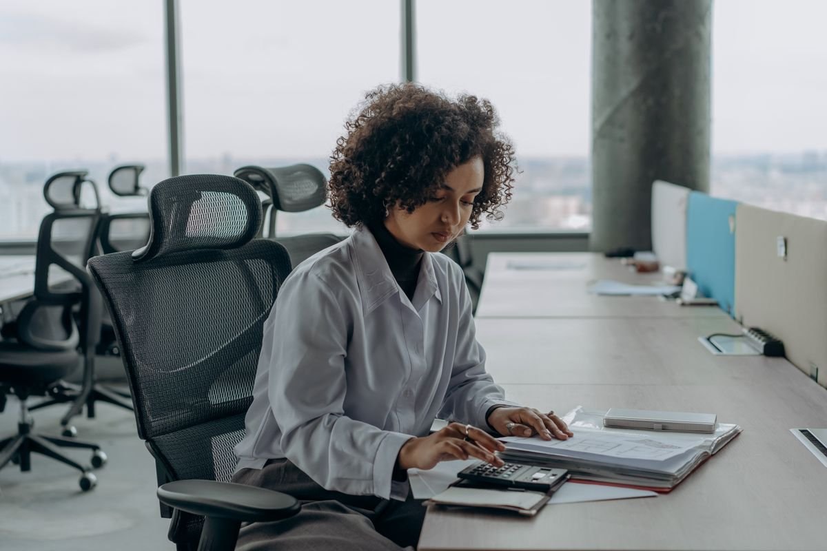 An office owner reviewing documents alone at her desk by a window